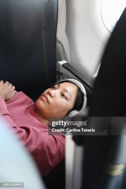 woman watching her phone on a flight - jet lag stockfoto's en -beelden