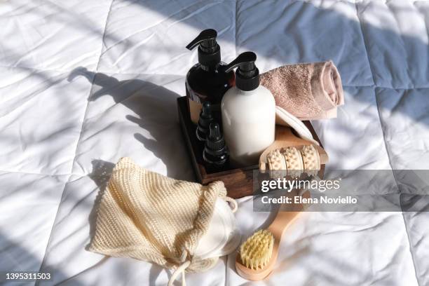 body and face care beauty bath set. bottles shampoo or shower gel  lotion, essential oil, cream, massage brushes and anti-cellulite.  shadow overlay, standing on the bed in the bedroom, sniffing a fluffy cat - bath spa stock-fotos und bilder