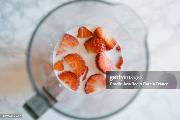 milk and sliced strawberries inside a jug - blended drink ストックフォトと画像