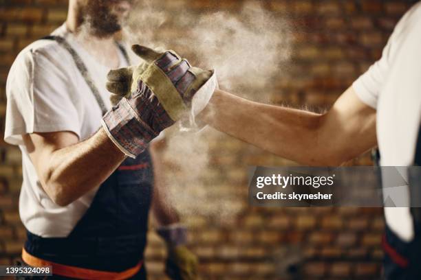 unrecognizable manual workers greeting each other at construction site. - empreiteiro de reparações imagens e fotografias de stock
