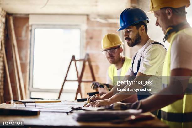 team of manual workers examining housing project while working at construction site. - building contractor bildbanksfoton och bilder