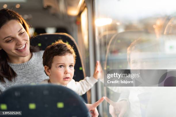 mother and son on a bus looking out of the window - bus window stock pictures, royalty-free photos & images