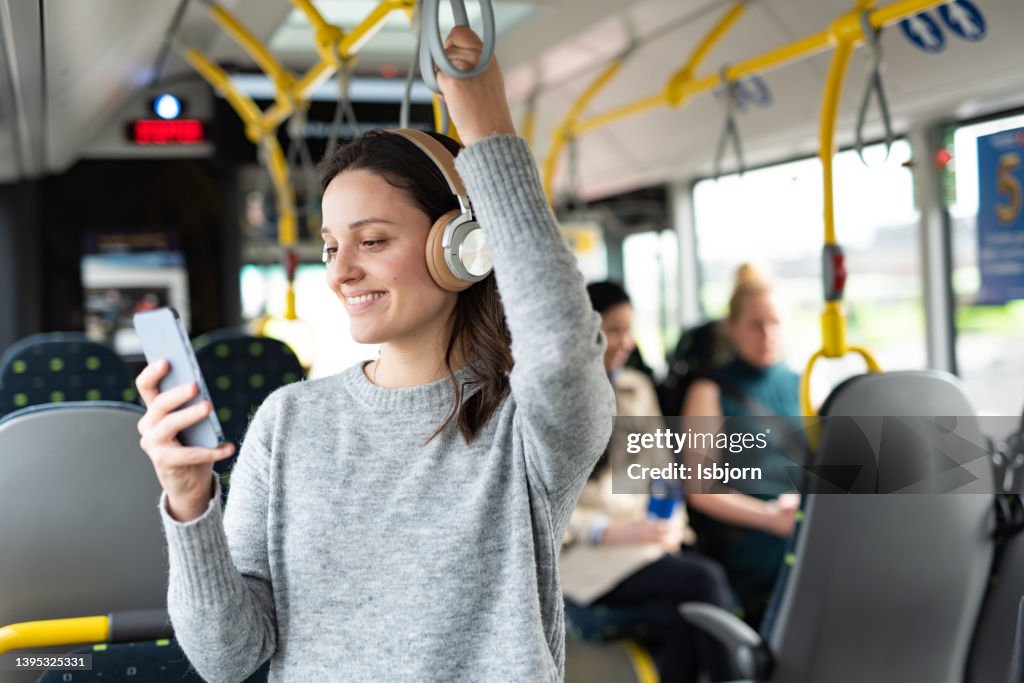 Frau, die im Bus am Telefon Musik hört