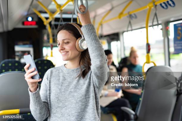 woman listening music on phone in bus - mobiliteit stockfoto's en -beelden