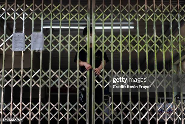 Beijing metro worker locks the gate of a subway station due to a concern of the spread of COVID-19 on May 4, 2022 in the Central Business District in...