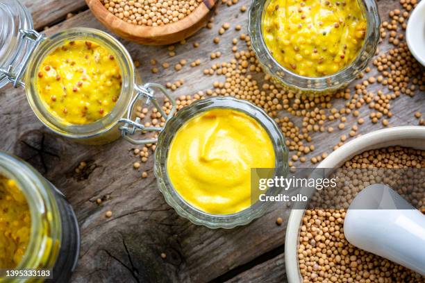 different types of mustard and mustard seeds on a rustic wooden board - yellow mustard stock pictures, royalty-free photos & images