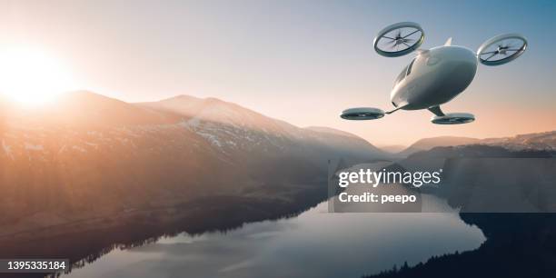 evtol electric vertical take off and landing aircraft flying through beautiful landscape at dawn - autonomous vehicles stock pictures, royalty-free photos & images