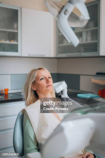 paciente femenina espera un examen en el consultorio dental - dental fear fotografías e imágenes de stock