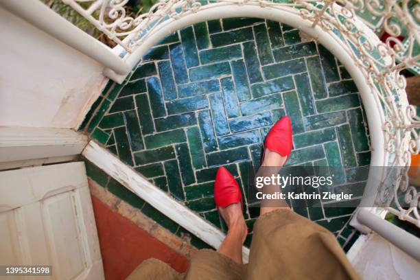 woman in red slippers standing on green tiled balcony, personal perspective - groene schoen stockfoto's en -beelden