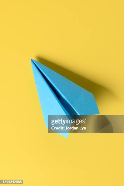 blue paper plane on yellow background - paper plane ストックフォトと画像