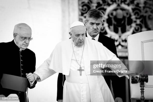 Pope Francis is helped by his assistants as he arrives in St. Peter's Square for his general weekly audience on May 04, 2022 in Vatican City,...