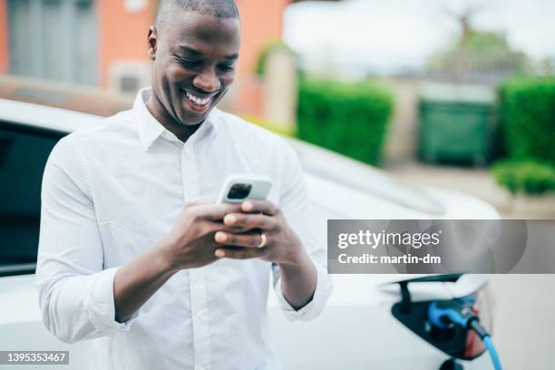 man charging electric car - hybrid vehicle stock pictures, royalty-free photos & images