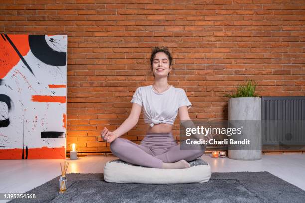 caucasian young woman meditiating in lotus position - cushion imagens e fotografias de stock