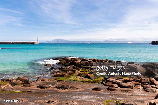 harbour past statue of sacred heart of jesus and punta del santo in distance, tarifa, cadiz, andalusia, spain - tarifa moors stock pictures, royalty-free photos & images
