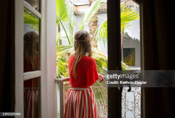woman standing on balcony of moroccan riad (small hotel), rear view - marrakesh stockfoto's en -beelden