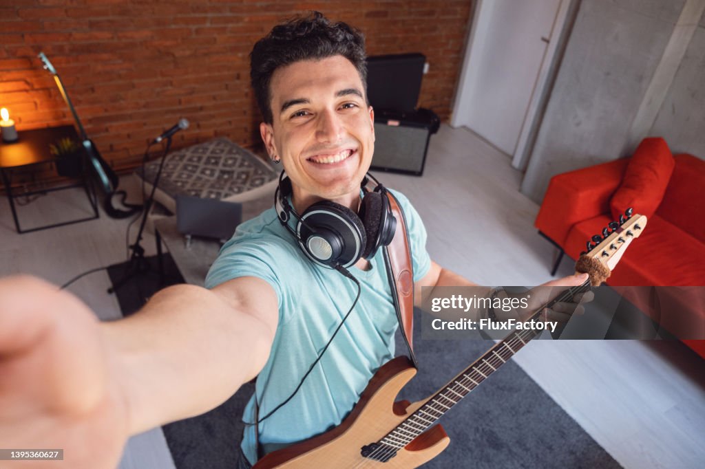 Joven guitarrista caucásico tomándose selfie