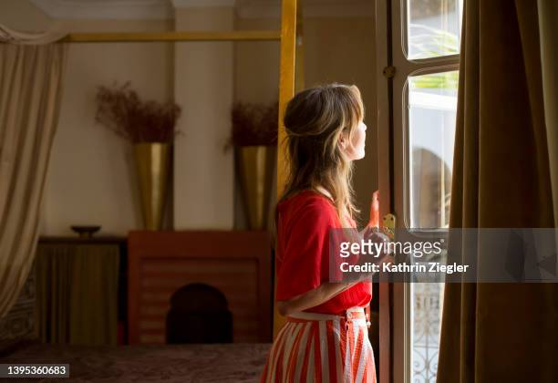 woman opening windows in hotel room, marrakech, morocco - lüften stock-fotos und bilder