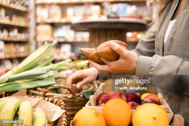 unrecognizable woman choosing fruit and vegetables at an organic organic market - zoete aardappel stockfoto's en -beelden