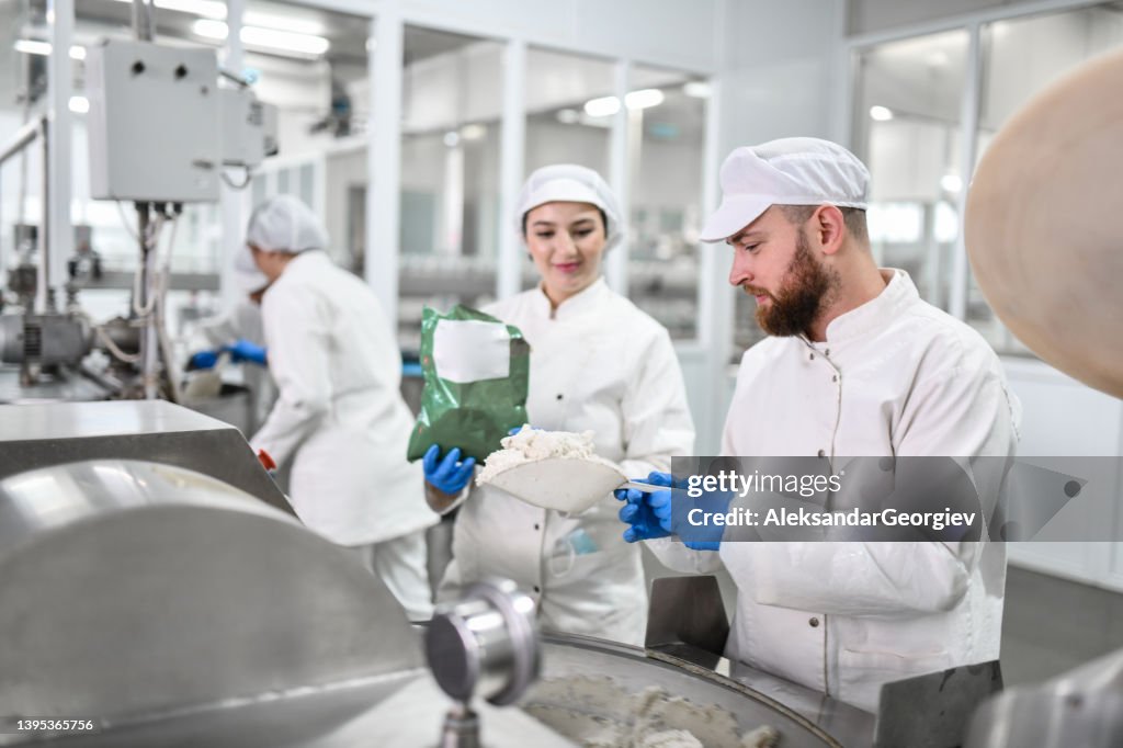 Bearded Male Worker In Food Processing Plant Using Female's Help To Prepare Cottage Cheese For Peppers