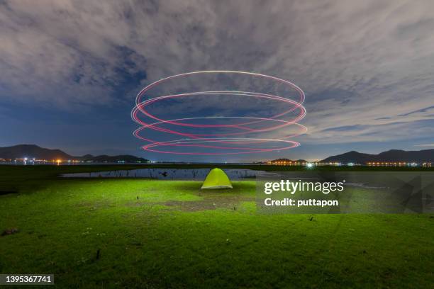 glowing spiral (light painting) of a drone over a beautiful tent at sunset. - radiacion electro magnetica fotografías e imágenes de stock