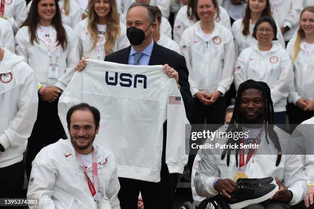 Second gentleman Doug Emhoff is given a pair of shoes and a Team USA shirt by Paralympic rugby player Chuck Aoki and Paralympic Basketball player...