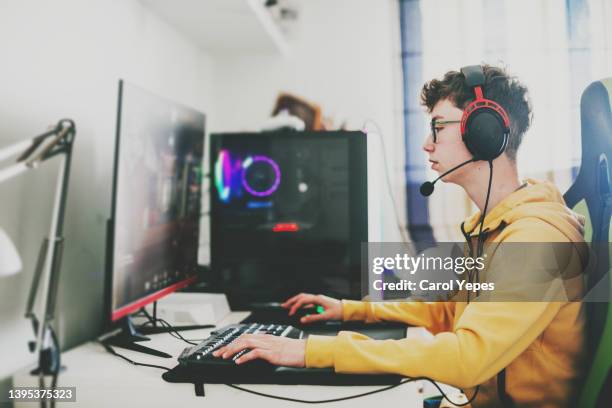 close up image of gamer tenager boy playing pc games with headset - gaming industry stock pictures, royalty-free photos & images