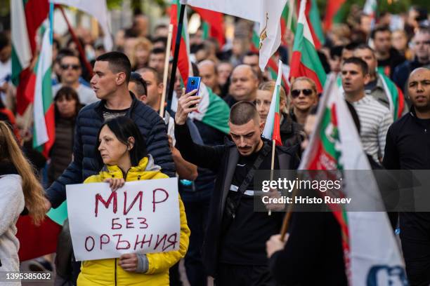 Woman holds a poster on which reads "Peace without weapons" as she attend a protest against military support for Ukraine on May 4, 2022 in Varna,...