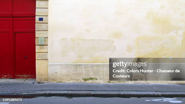 facade of an old mansion with red door, empty sidewalk and street in paris - le mur photos et images de collection