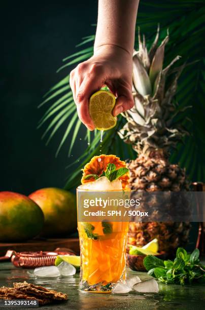 cropped hand of woman holding drink on table - mango juice stockfoto's en -beelden