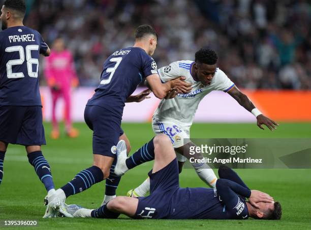 Ruben Dias of Manchester City clashes with Vinicius Junior of Real Madrid as Aymeric Laporte of Manchester City lays injured during the UEFA...