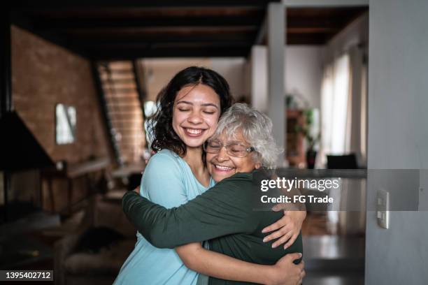 granddaughter and grandmother hugging each other at home - grandparent stockfoto's en -beelden