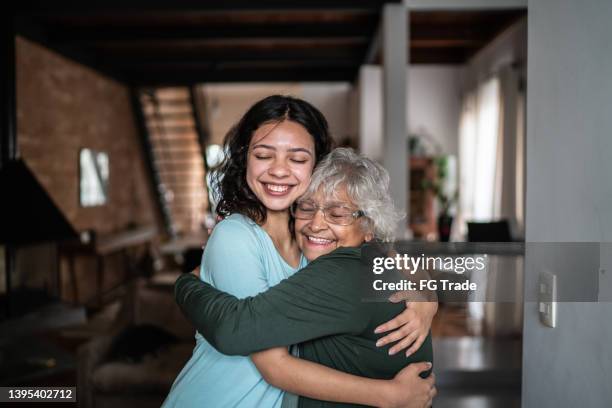 granddaughter and grandmother hugging each other at home - hugging grandmother stock pictures, royalty-free photos & images