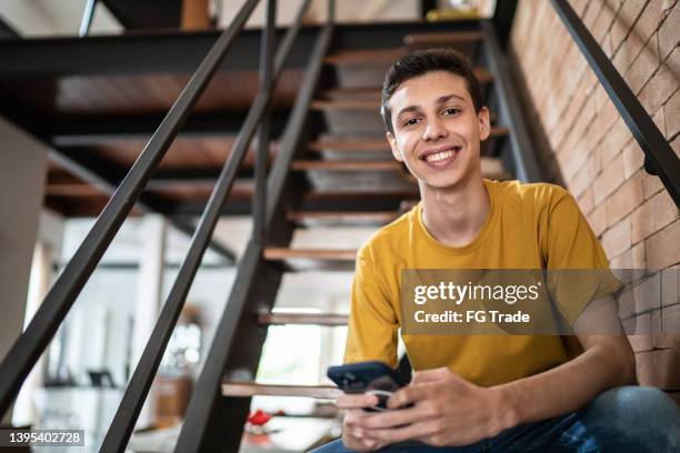 retrato de un joven usando el teléfono móvil en casa - 18 19 años fotografías e imágenes de stock