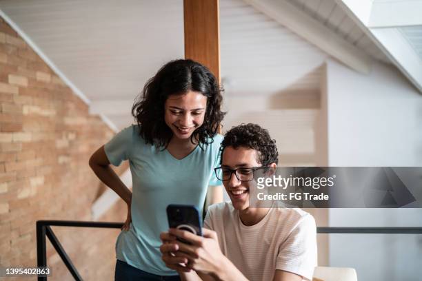 siblings using the mobile phone at home - camera girls stock pictures, royalty-free photos & images