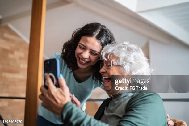 grandmother and granddaughter using the mobile phone at home - modern family media call stockfoto's en -beelden