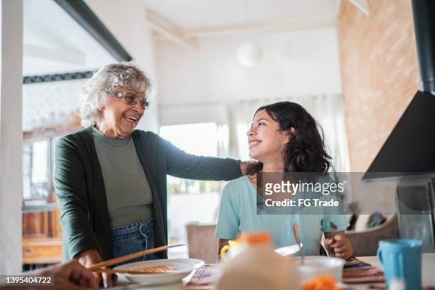 großmutter und enkelin unterhalten sich beim frühstück zu hause - familie zuhause essen stock-fotos und bilder