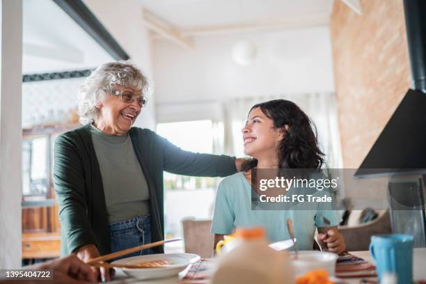 grandmother and granddaughter talking while having breakfast at home - generation gap stock pictures, royalty-free photos & images