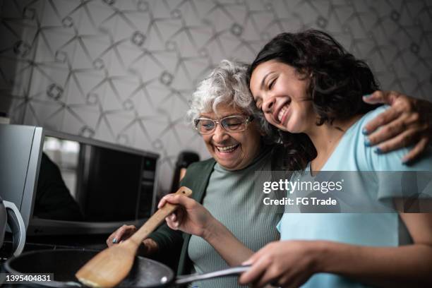 granddaughter and grandmother cooking at home - cooking stock pictures, royalty-free photos & images