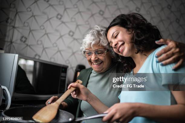 granddaughter and grandmother cooking at home - vitality food stock pictures, royalty-free photos & images