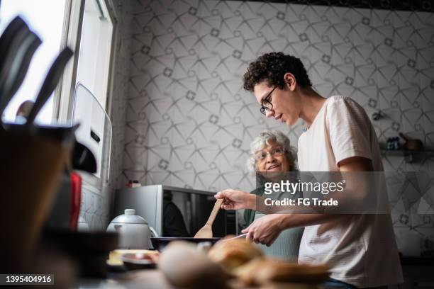 grandson and grandmother cooking at home - grandparent stockfoto's en -beelden