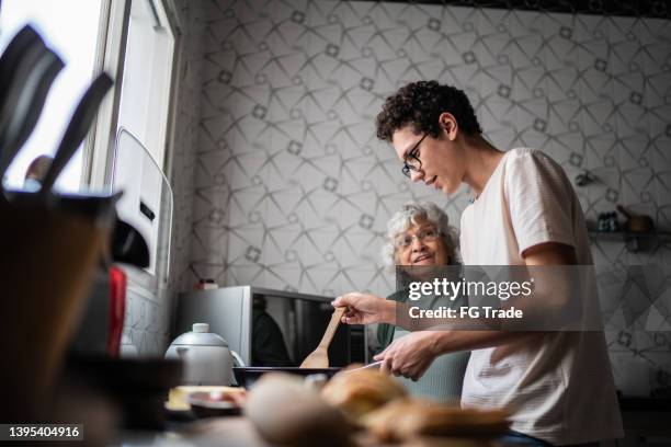 grandson and grandmother cooking at home - senior lunch stock pictures, royalty-free photos & images