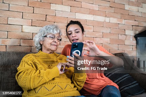 Granddaughter helping grandmother to use the mobile phone at home Granddaughter helping grandmother to use the mobile phone at home