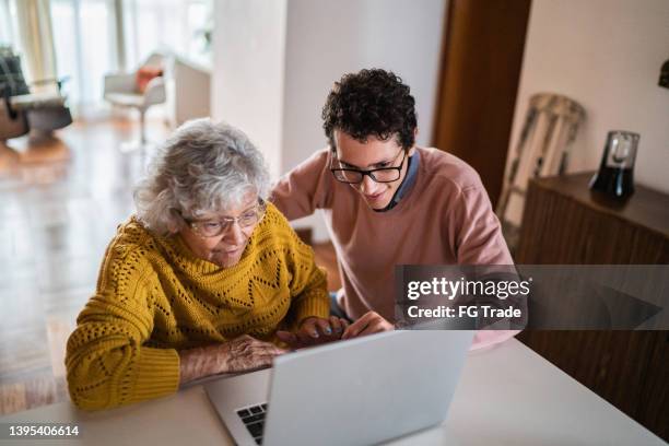 grandson and grandmother using laptop at home - old woman young man stock pictures, royalty-free photos & images