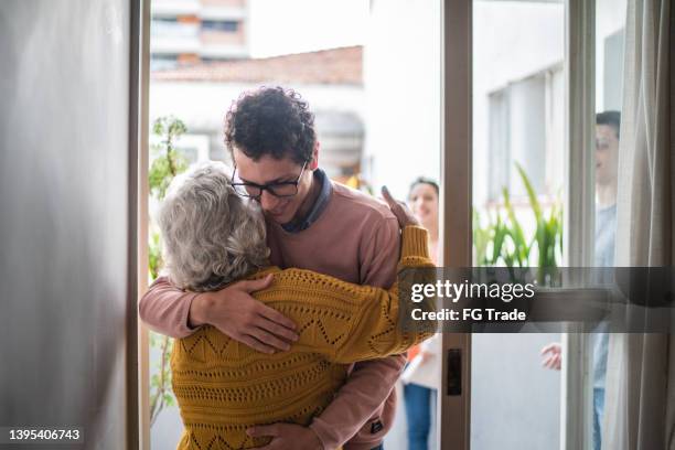 grandmother welcoming grandson at home - housewarming stock pictures, royalty-free photos & images