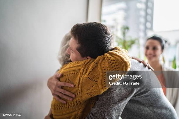 abuela dando la bienvenida al nieto en casa - old woman young man fotografías e imágenes de stock