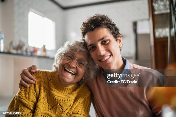 retrato de una mujer mayor feliz y su nieto en casa - old woman young man fotografías e imágenes de stock