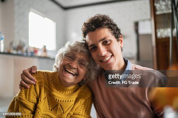 portrait of happy senior woman and her grandson at home - old woman young man stock pictures, royalty-free photos & images