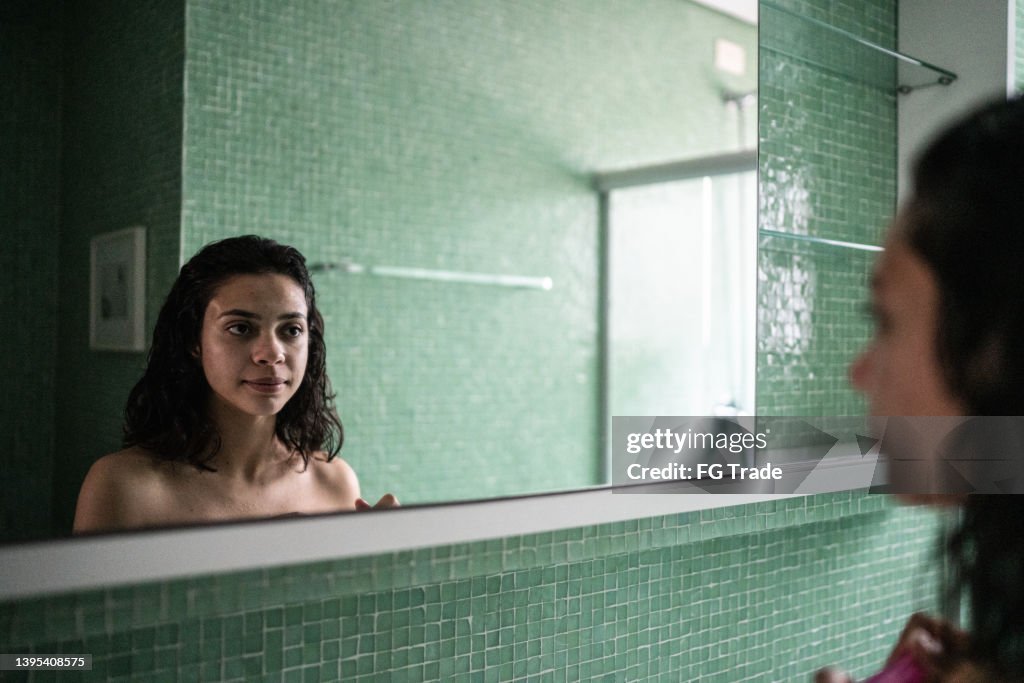 Teenage girl looking in the mirror at home