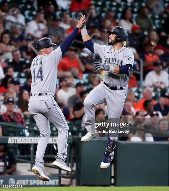 Eugenio Suarez of the Seattle Mariners receives a high five from third base coach Manny Acta after hitting a two run home run in the seventh inning...