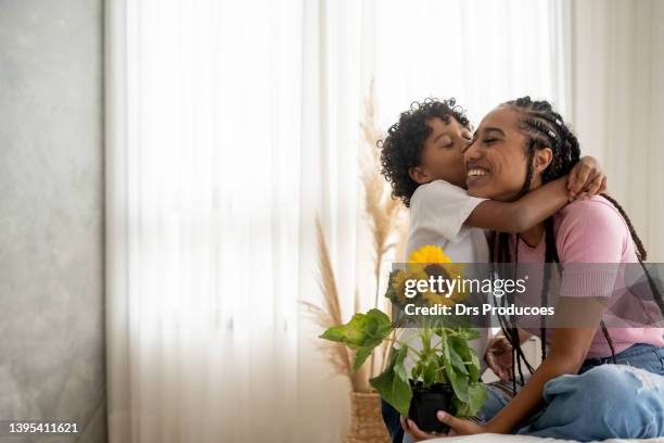 figlio che consegna il fiore alla sua madre per la festa della mamma - real people lifestyle and family foto e immagini stock